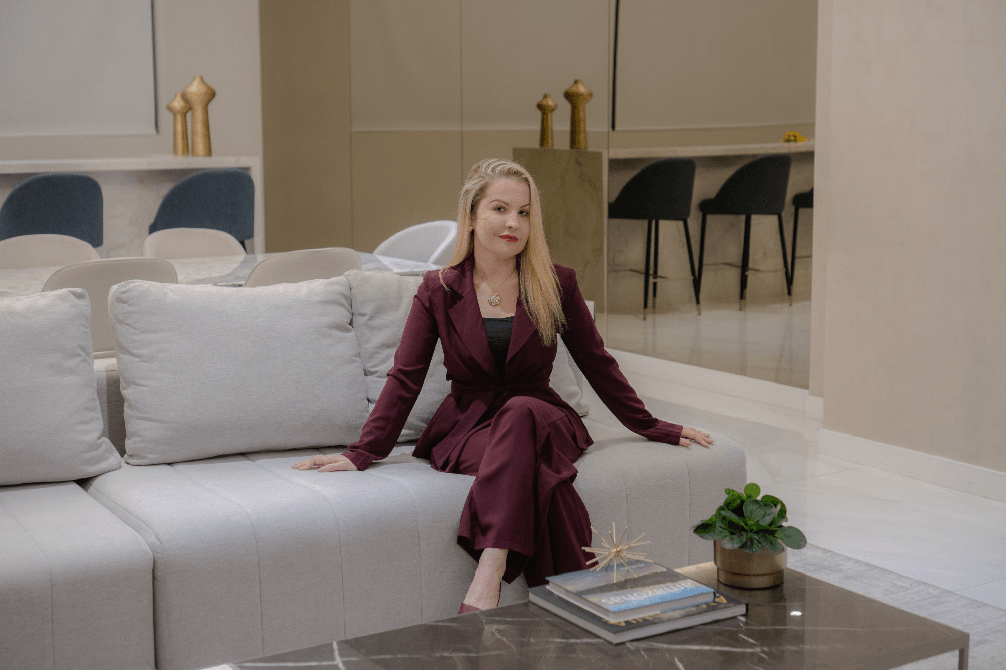 Dra. Naiayde Monte sentada em um sofá claro, em ambiente sereno.
